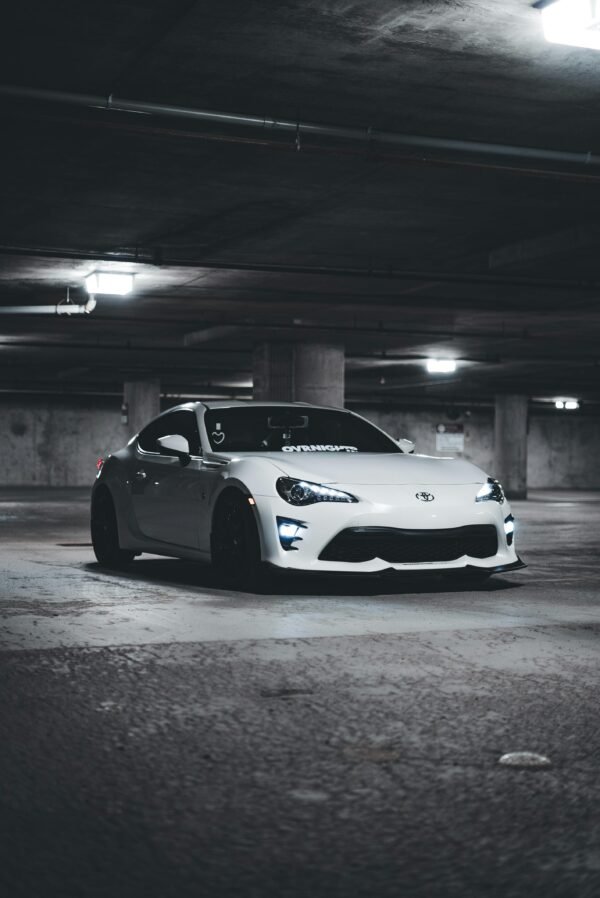 White sports car parked in dimly lit underground garage, capturing luxury automotive elegance.